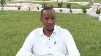 Journalist Abdinur Mohamed Ahmed sits on the grass at Peace Garden in Mogadishu.