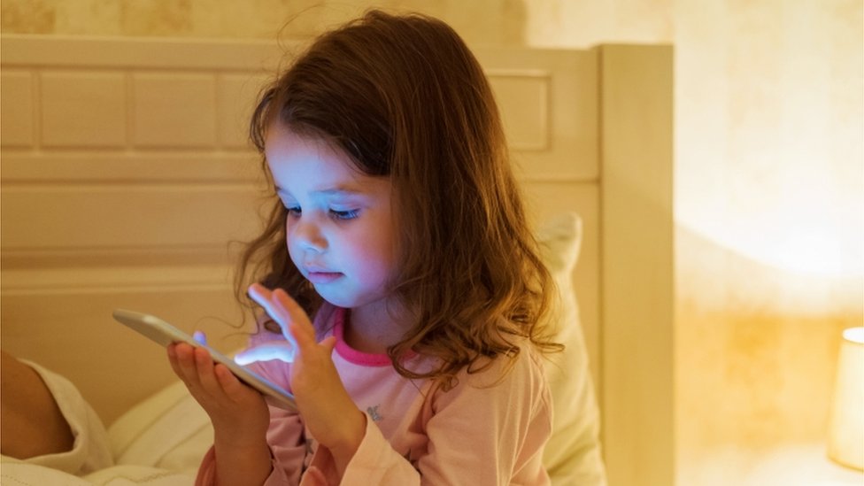 Duas Meninas No Sofá à Noite Com Um Tablet Digital. Jogos