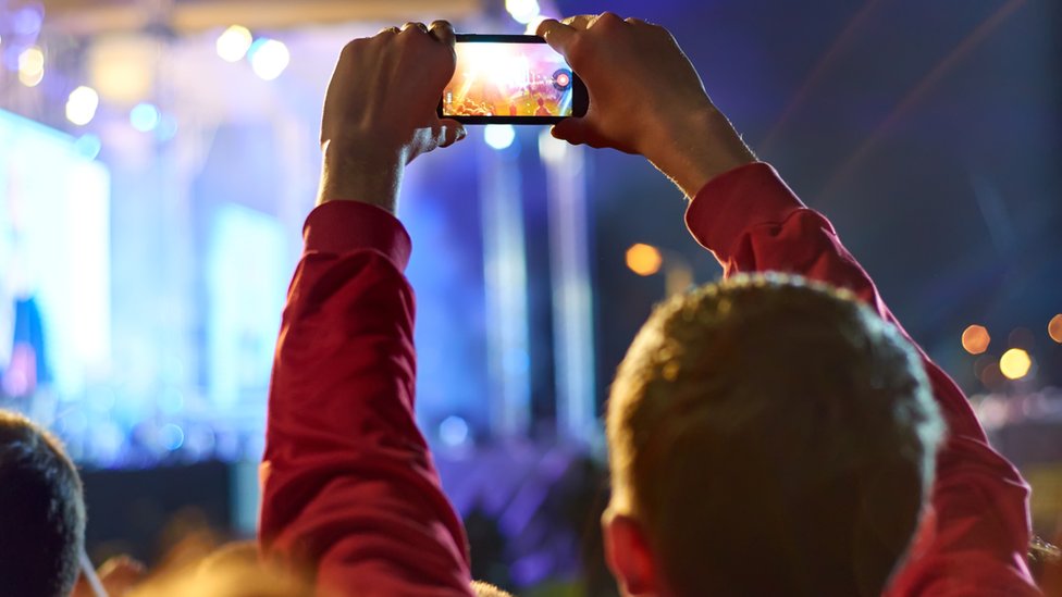 Man videoing concert on mobile phone