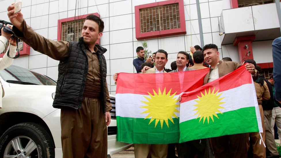 أكراد يلتقطون صورا مع علم إقليم كردستان العراق