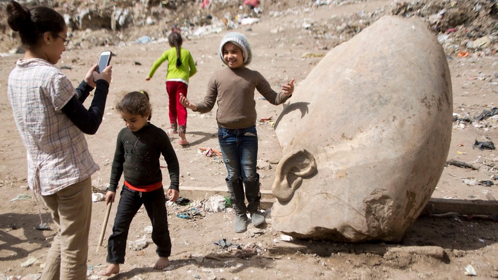 Una niña se retrata junto a uno de los restos de la estatua que pudo haber pertenecido al faraón Ramsés II.
