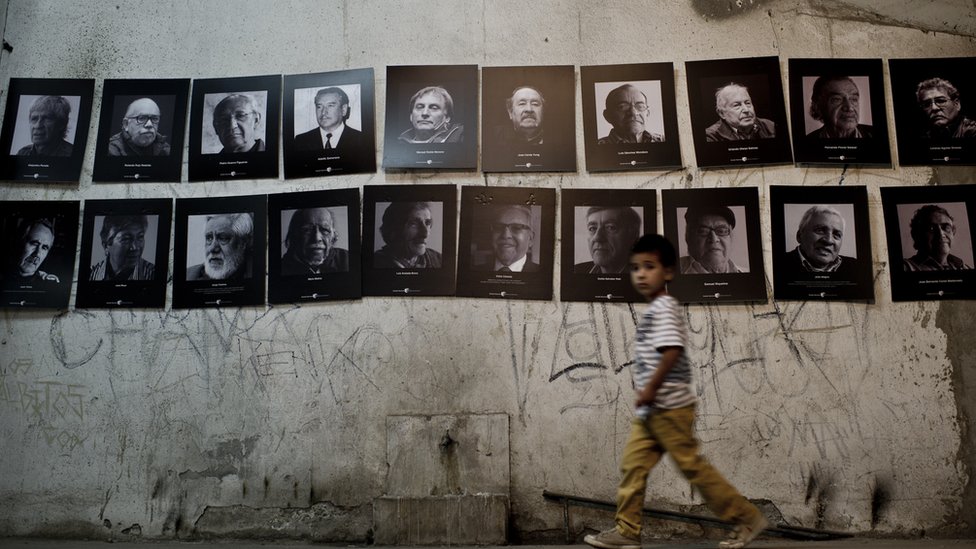 Un niño camino por delante de las fotos de los prisioneros políticos en el Estados de Santiago en Chile.