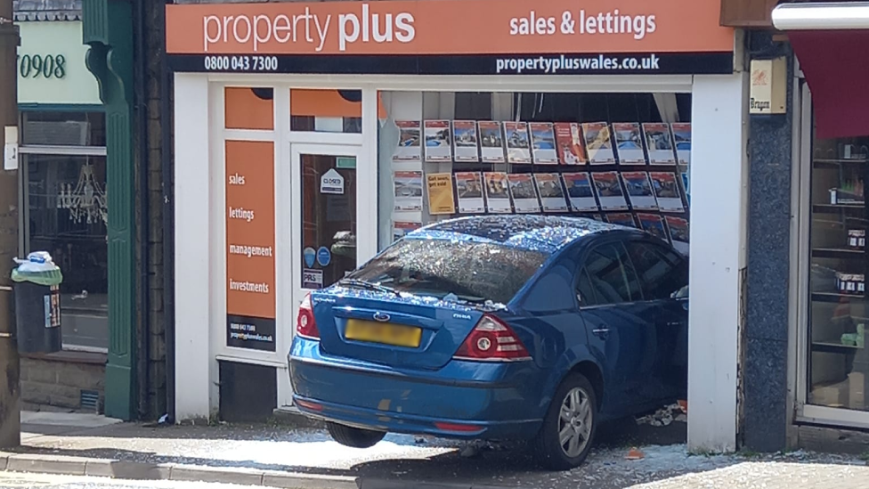 Empty car crashes through shop window