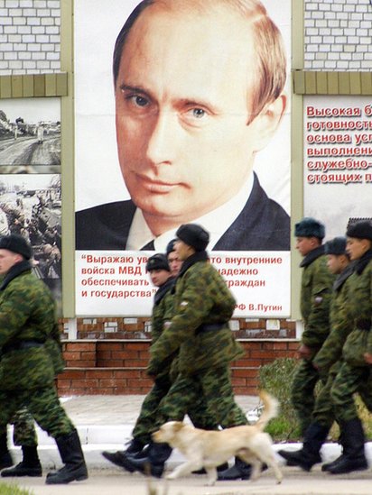 جنود روس يمشون بجانب صورة بوتين في إحدى الثكنات العسكرية في الشيشان