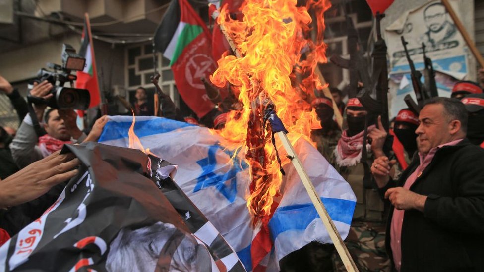 Manifestantes palestinos queman la bandera de Israel.