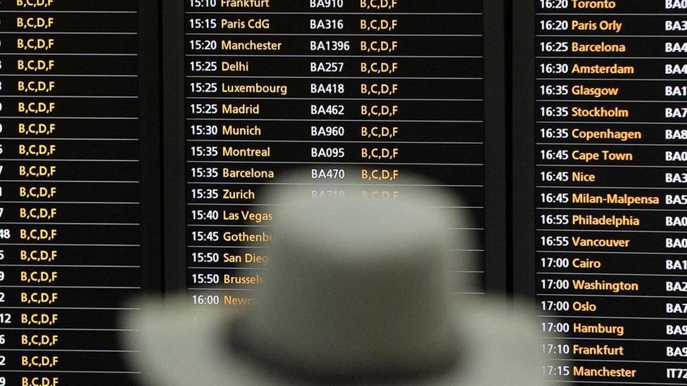 Una persona mirando un tablero que anuncia las salidas y llegadas de aviones en un aeropuerto