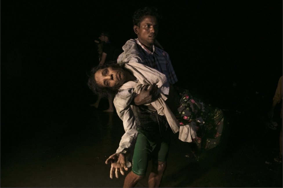 Nobi Hossain carga a Sona Banu hacia la orilla del río Naf. Como ellos, medio millón de rohingyas ha huído a causa de la violencia militar del ejército de Myanmar.