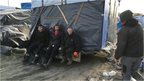 Migrants moving makeshift shacks away from the motorway