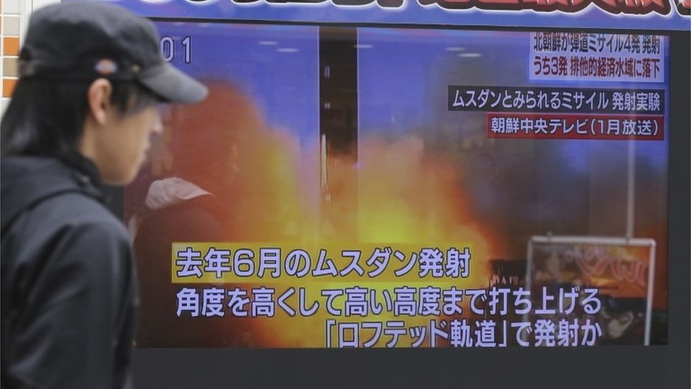 Una persona pasa por delante de una pantalla de televisión que informa sobre el lanzamiento de misiles de Corea del Norte en Tokio, Japón.
