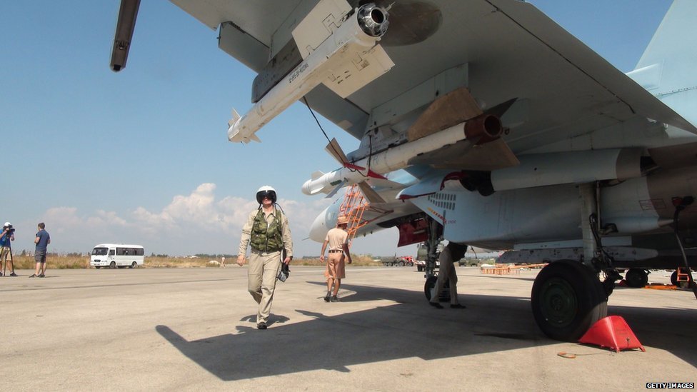 A picture taken on October 3, 2015 shows Russian air force pilots and technicians checking a Russian Sukhoi Su-30 SM jet fighter