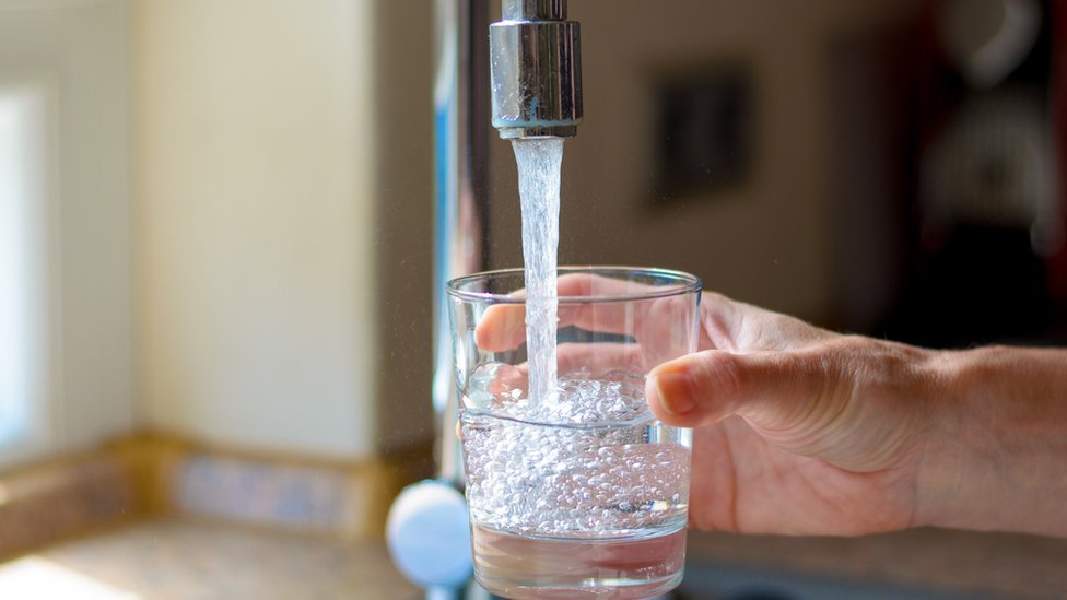 Una persona sirviéndose un vaso de agua