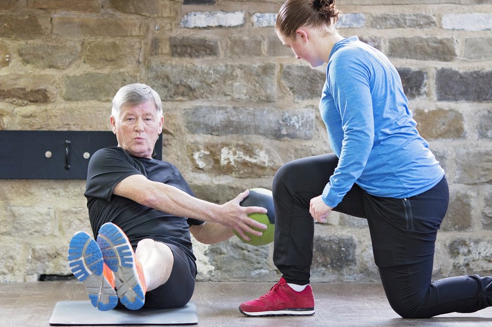 Senior man exercising with personal trainer