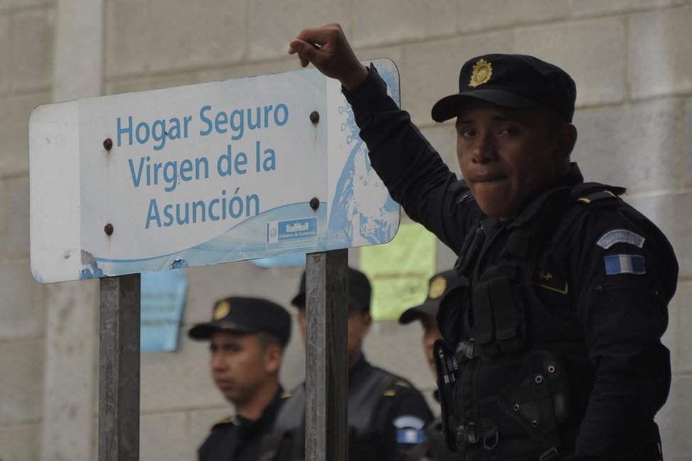 Policía apoyado en un cartel que dice Hogar Seguro Virgen de la Asunción el 15 de marzo de 2017.