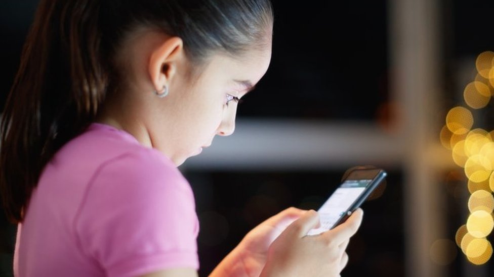 niña usando teléfono móvil