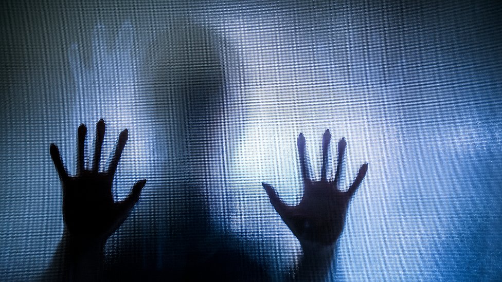 Silueta atrapada detrás de una superficie transparente.
