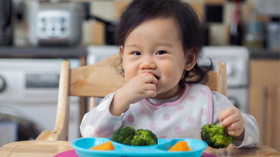 Bebé comiendo verduras con la mano