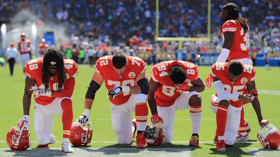 Jugadores de la NFL arrodillados durante el himno estadounidense.