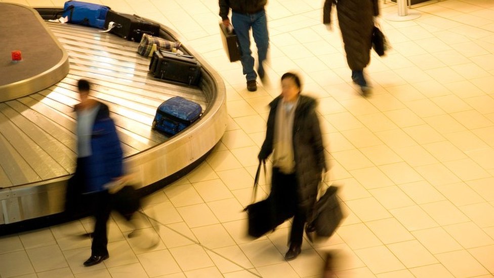 Personas que caminan cerca de las correas de entrega de maletas