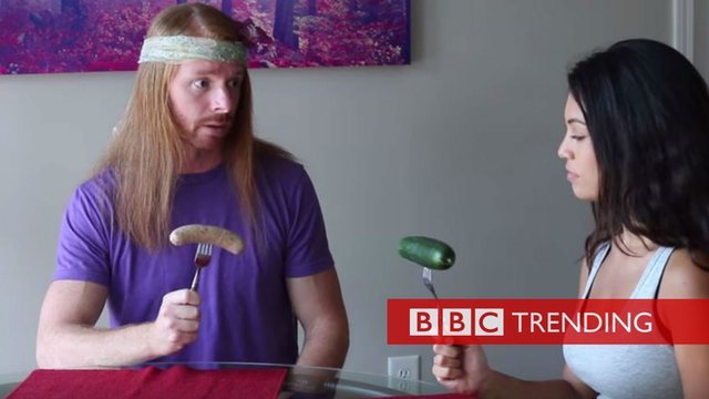 Image from video 'If Meat Eaters Acted Like Vegans'. Man holding sausage, woman holding cucumber. 