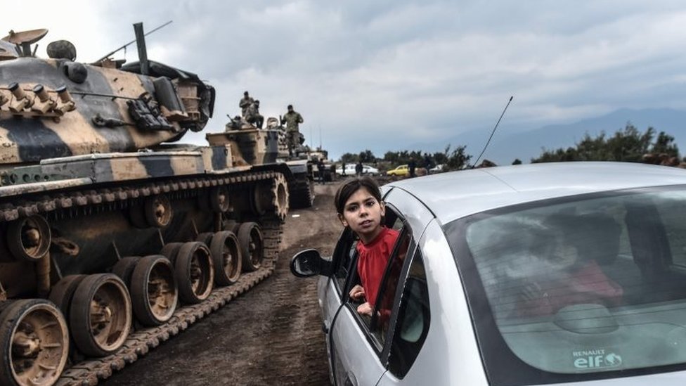 Una niña turca se asoma por la ventanilla de un automóvil para observar cómo los tanques y soldados del ejército turco se reúnen cerca de la frontera siria en Hassa, en la provincia de Hatay, el 21 de enero de 2018.