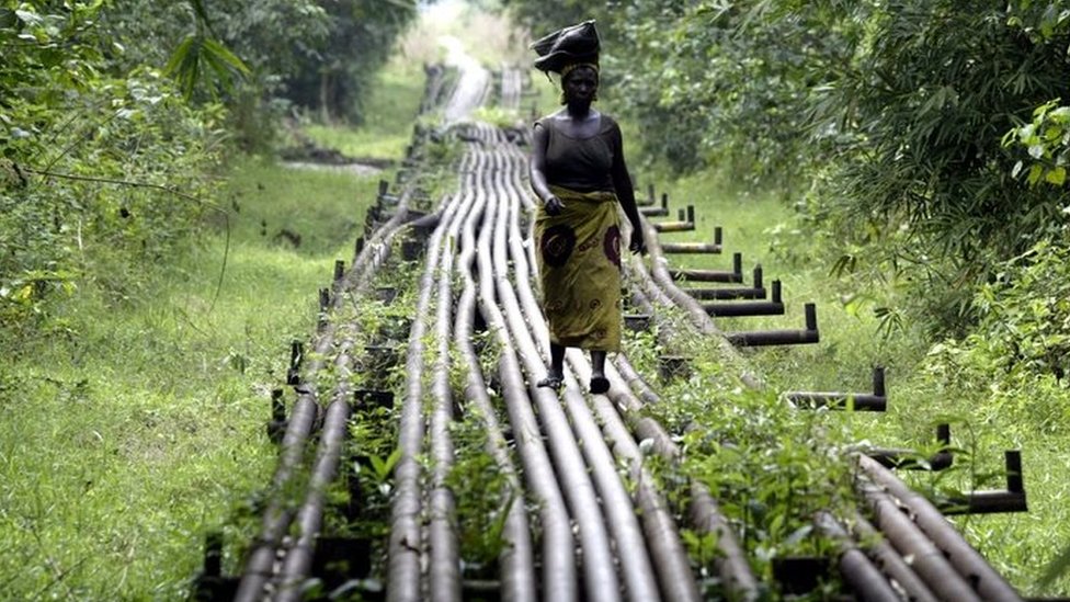 امرأة تسير وفق أنابيب نقل النفط في نيجيريا