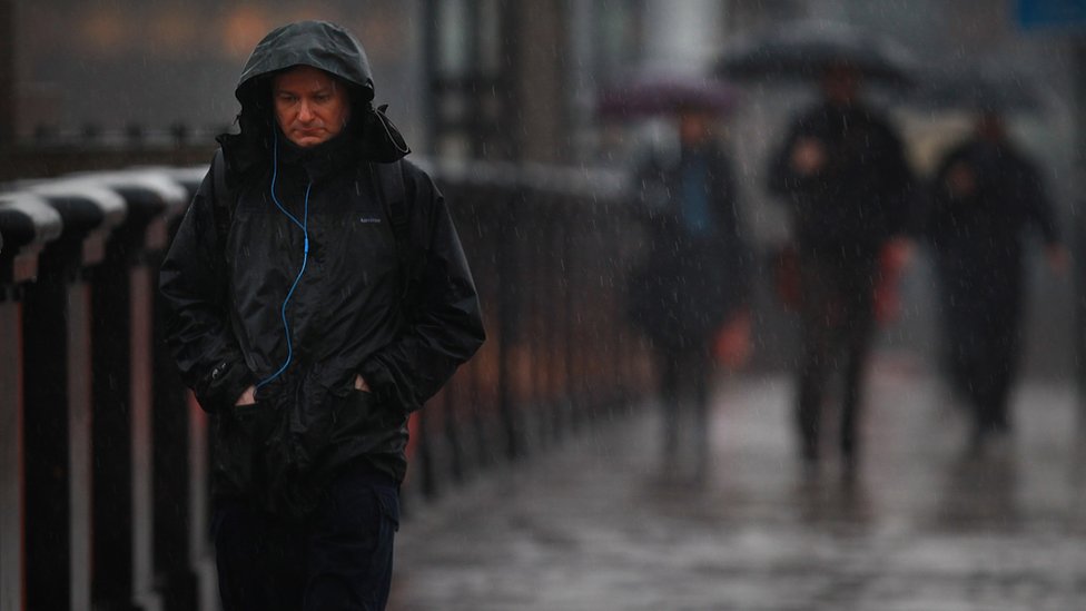Un hombre caminando bajo la lluvia