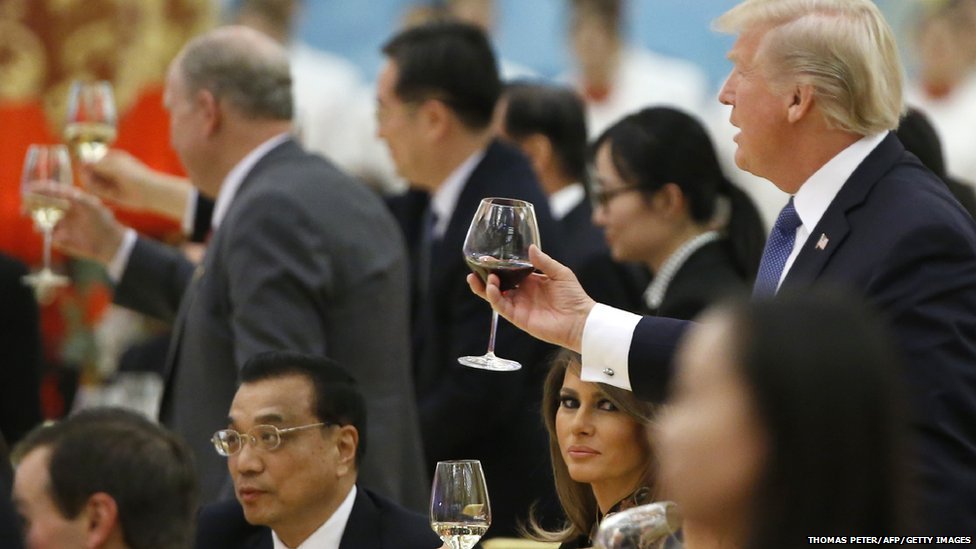 President Donald Trump raising a toast while his wife Melania sits by his side