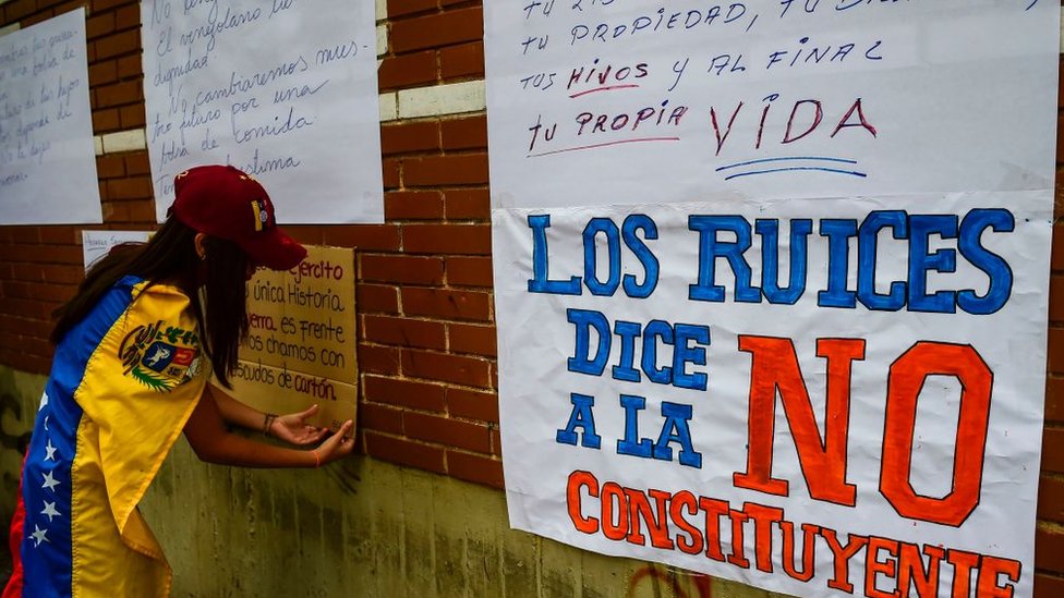 Una manifestante pega carteles contra la Constituyente.