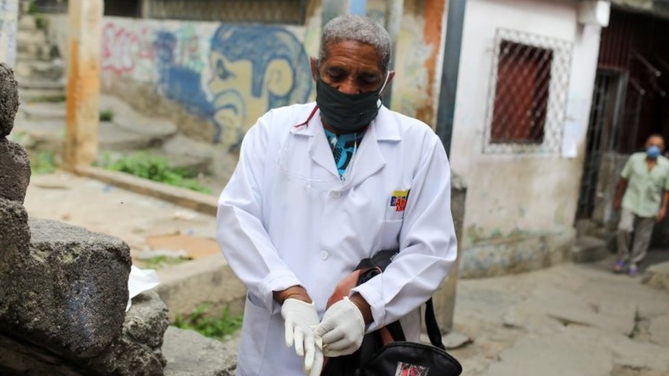 A doctor puts on gloves during a walking round at the low-income neighbourhood of Las Mayas, as cases rise amid the coronavirus disease (COVID-19) outbreak, in Caracas, Venezuela July 14, 2020.