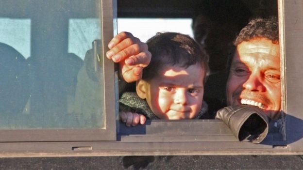 طفل يغادر المدينة ويلقي نظرة على منزله في شرق حلب