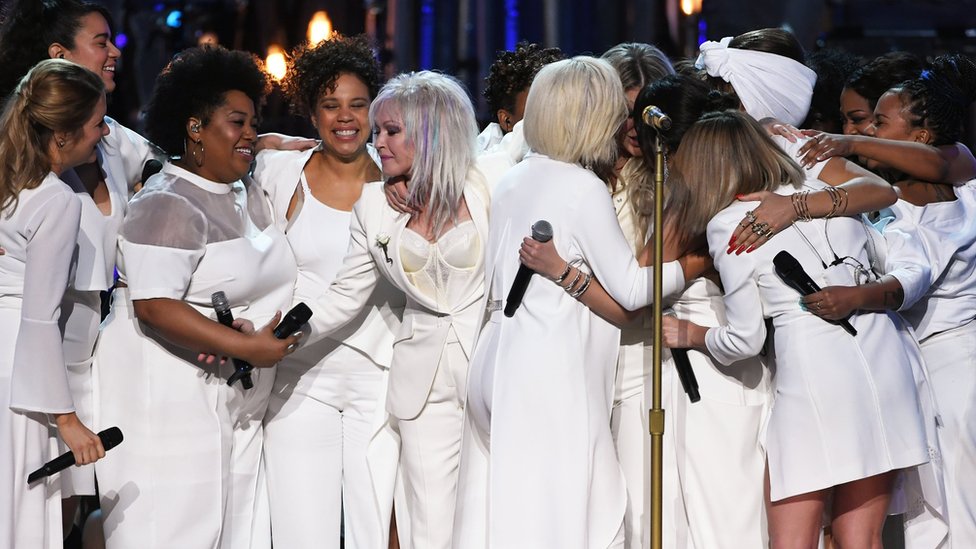 Las cantantes que acompañaron a Kesha en su presentación la abrazan al final de la misma.