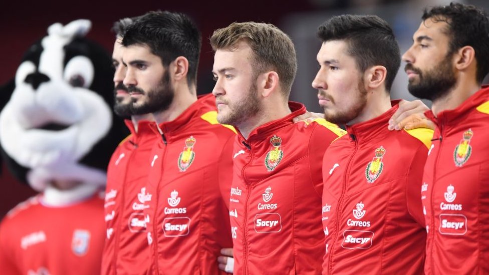 Jugadores de la selección española de balonmano escuchan el himno nacional.