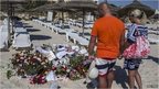 Tourists pay their respects in front of a makeshift memorial at the beach near the Imperial Marhaba resort, which was attacked by a gunman in Sousse, Tunisia, June 29, 2015.