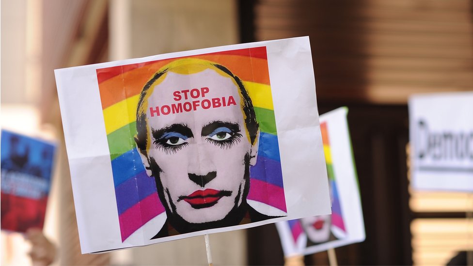 Un manifestante sostiene una imagen que representa a Vladimir Putin con los labios pintados.