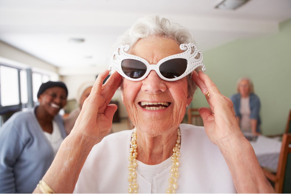 Mujer mayor con lentes de sol de diseño divertido sonriendo.