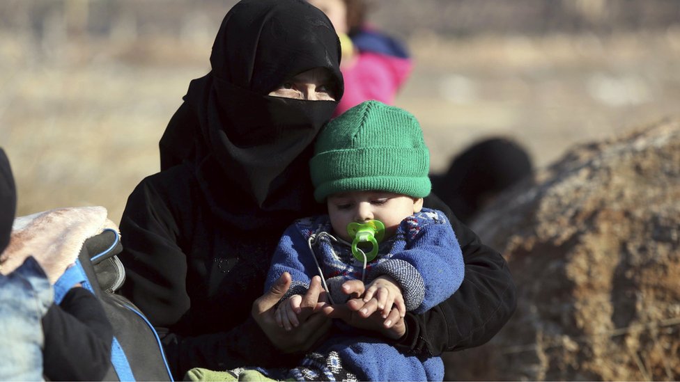 امرأة سورية تجلس مع طفلها