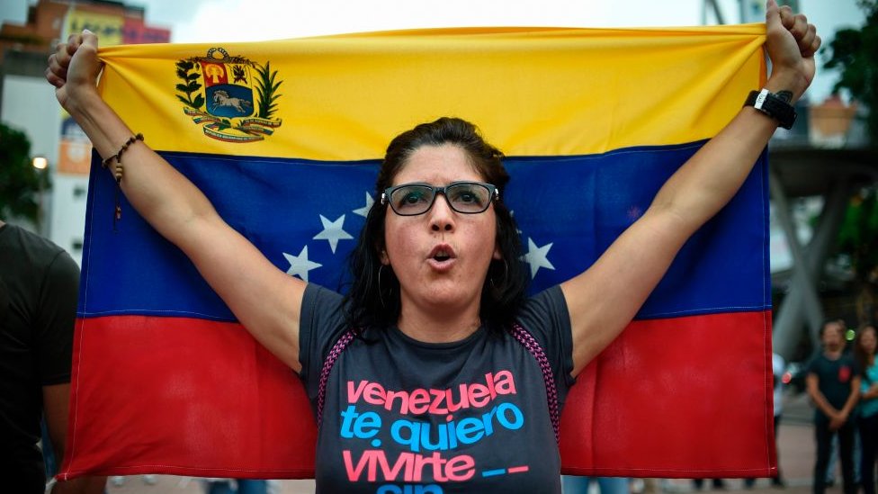 Una mujer con una bandera de Venezuela.