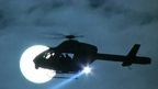 Helicopter silhouetted against Moon