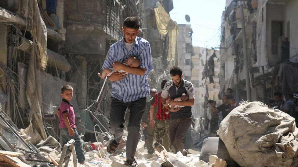 نازح سوري يحمل طفلا