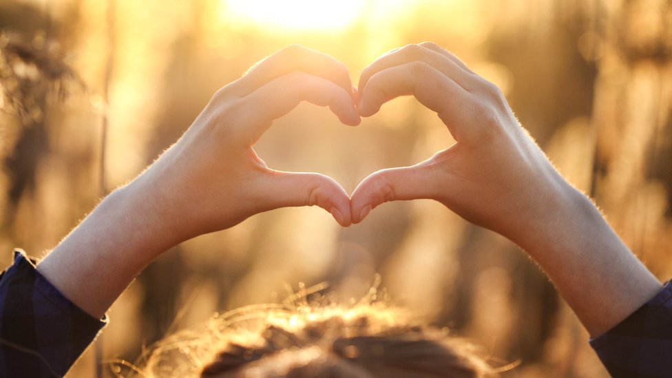 Mujer formando un corazón con sus manos.