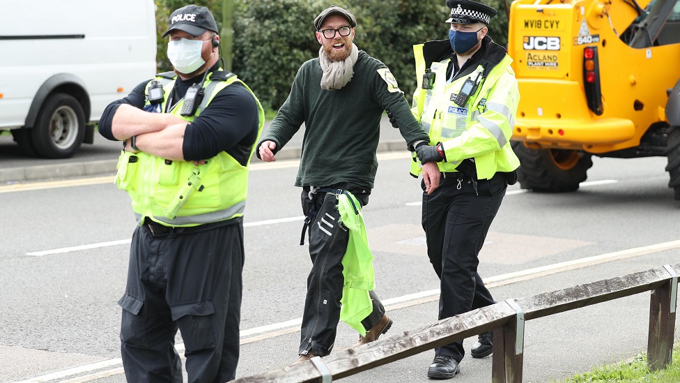 An Extinction Rebellion protester is led away by police from outside the Newsprinters printing works at Broxbourne, Hertfordshire