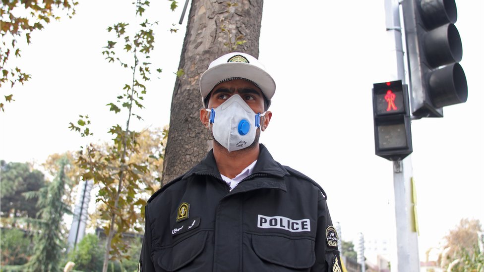 شرطي يرتدي كمامة في أحد شوارع طهران