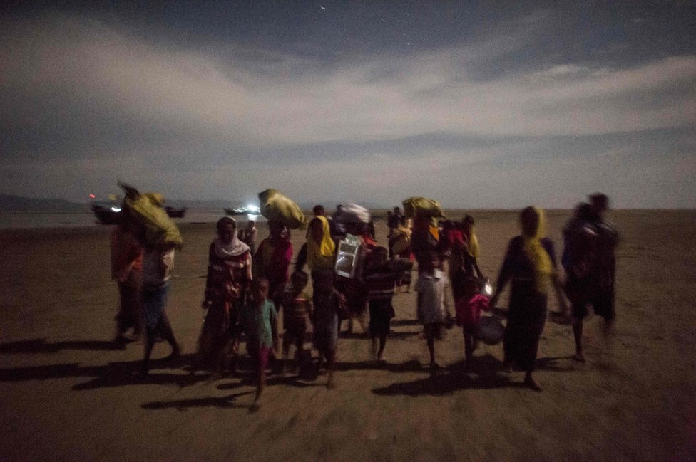 Un grupo de refugiados camina en la noche tras cruzar el río Naf, en su escape de la brutalidad del ejército de Birmania.