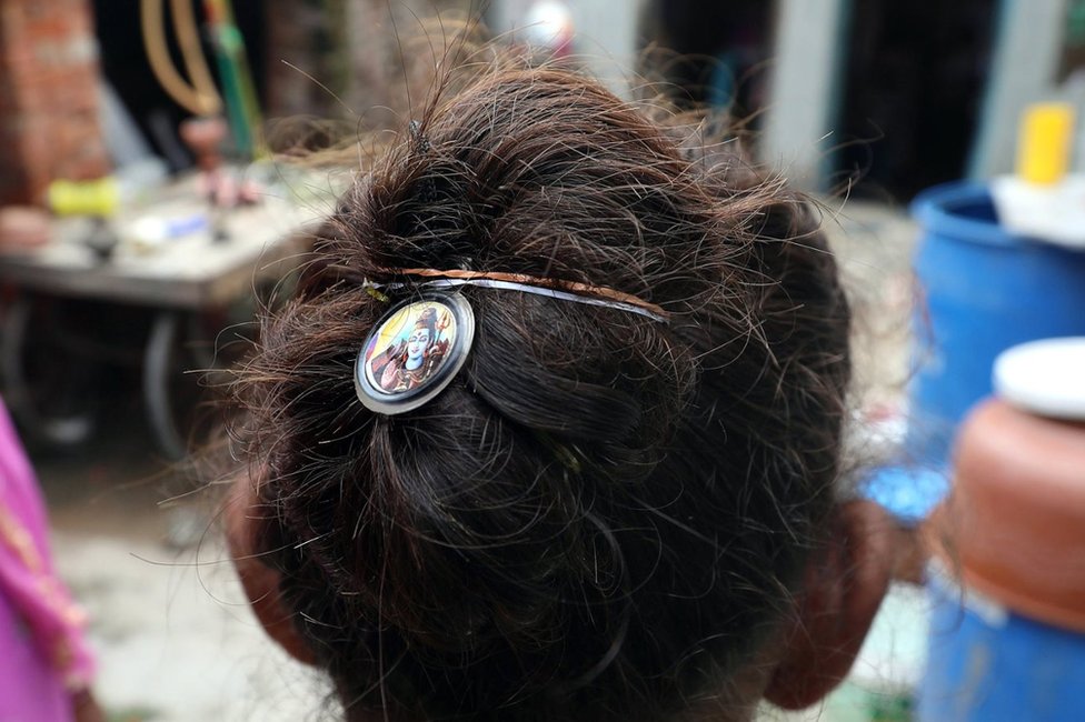 Seorang perempuan India meletakkan gambar dewa Hindu Shiva pada rambutnya untuk perlindungan setelah beberapa perempuan dipotong kepangnya oleh seorang yang tidak dikenal di kampung Kanganheri, pinggiran kota Delhi, India, 01 Agustus 2017
