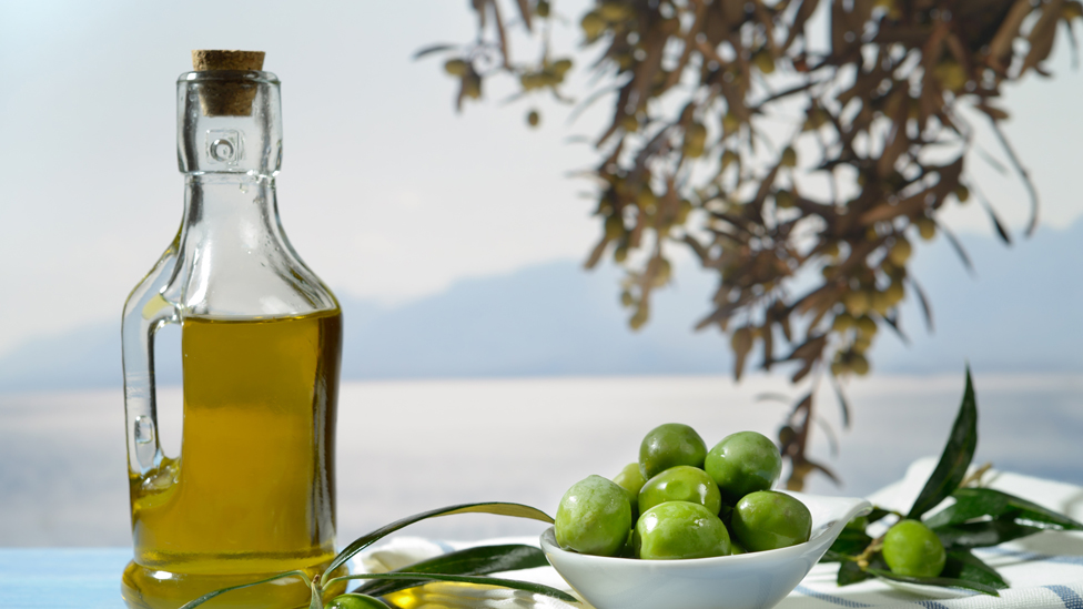 Botella de aceite de oliva y un plato con aceitunas