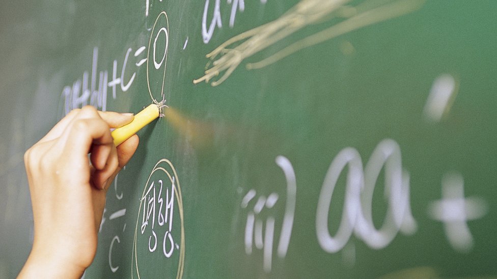 Mano escribiendo en un pizarrón.