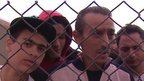 Ibrahim Maarouf (c) and other migrants behind a wire fence at military base in Dhekelia