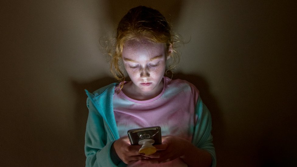 Dois adolescentes, menino e menina, jogam jogo para celular em smartphones