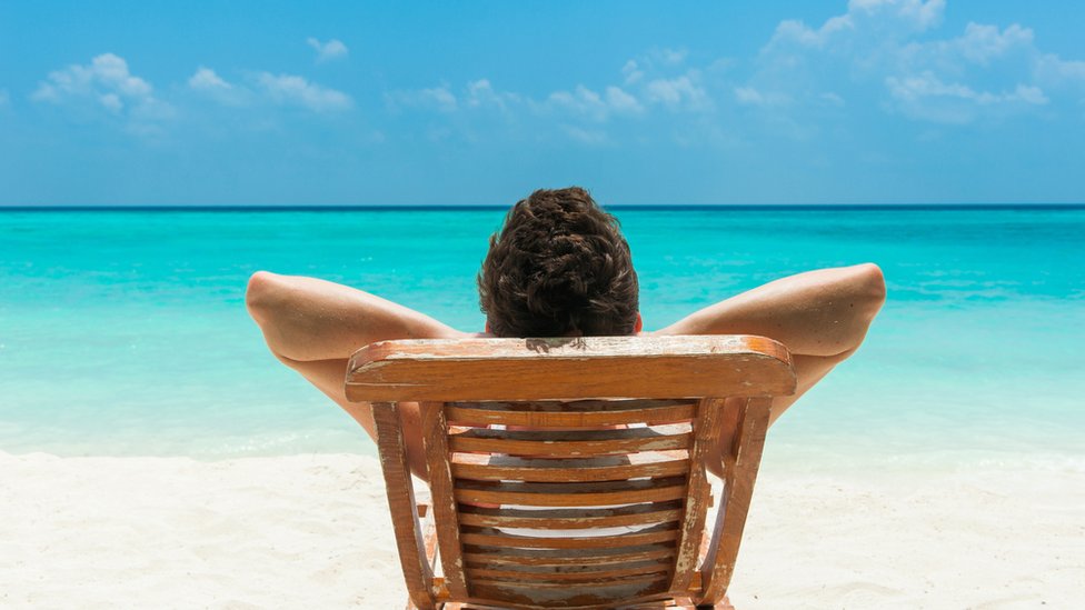 Hombre acostado en silla de extensión en la playa