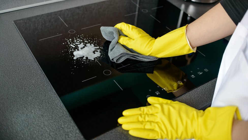 Una persona limpiando una cocina eléctrica